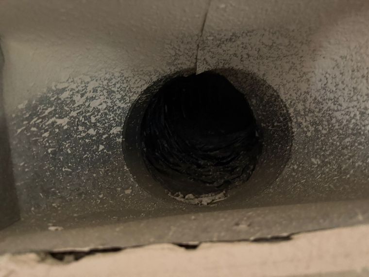 Dust coating the inside of a supply duct opening before air duct cleaning