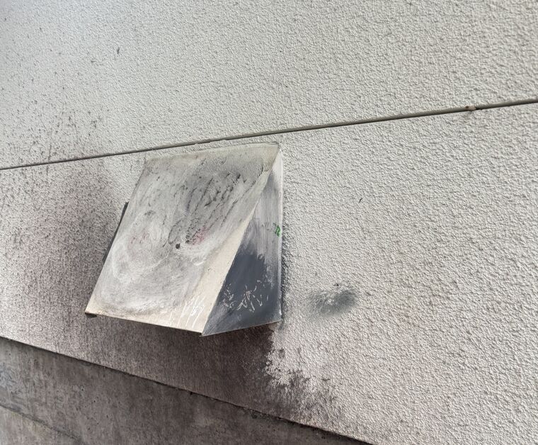 Outside dryer vent flap with lint and dark staining on the wall
