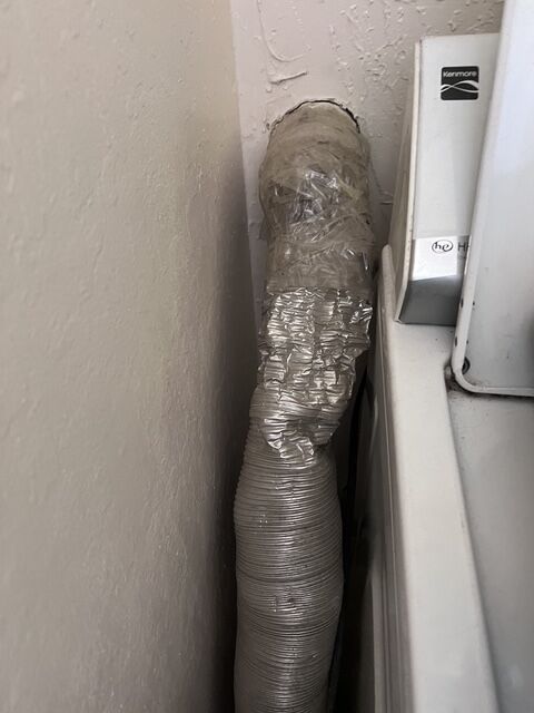 Crumpled foil dryer hose squeezed behind a dryer