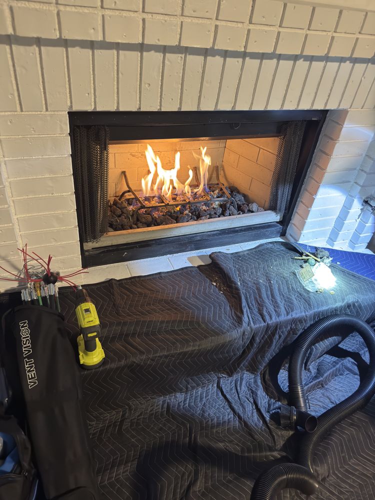 Fireplace sealed with drop cloths and vacuum staged during a chimney sweep
