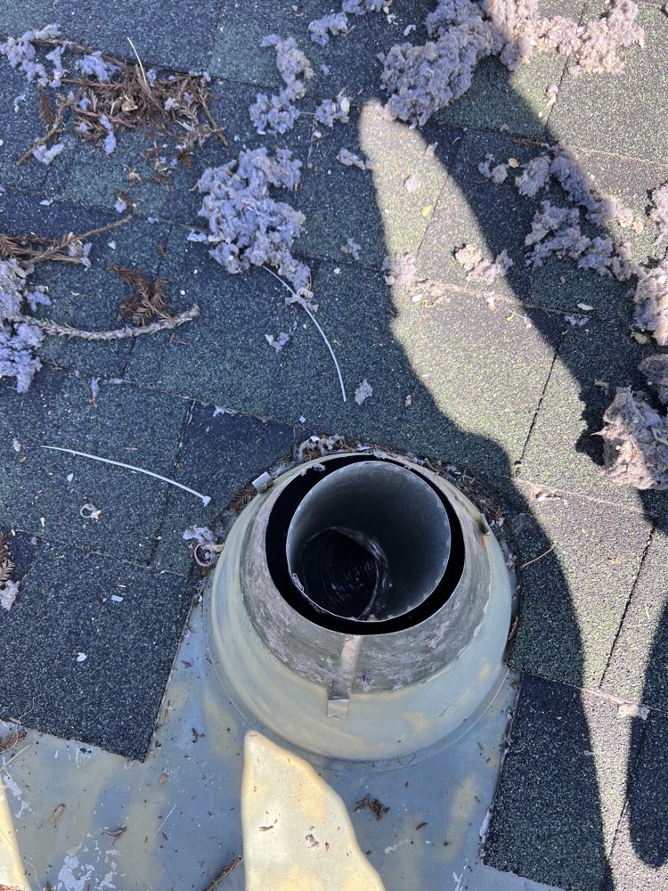 Opened roof vent showing compacted lint buildup before cleaning