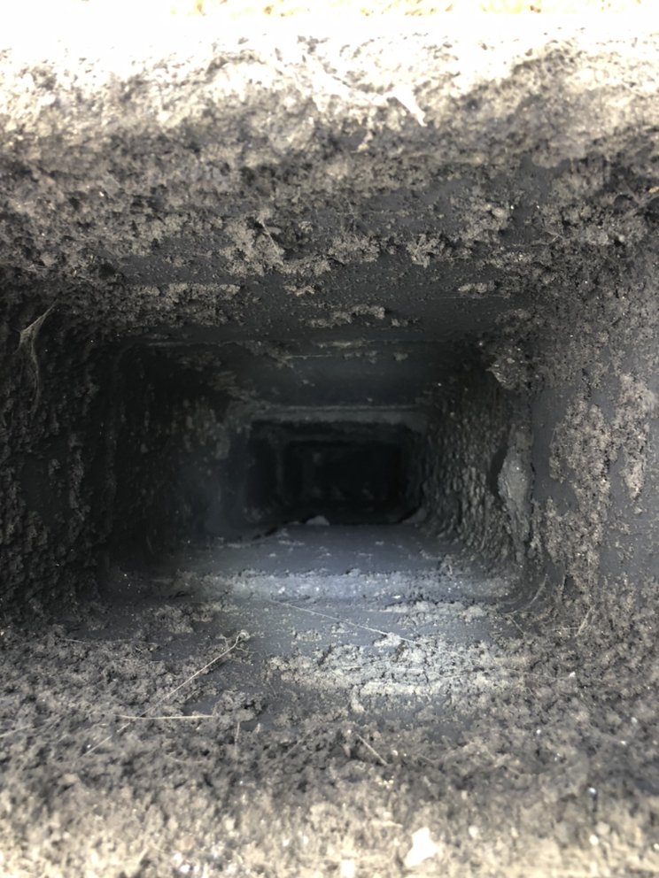 Before cleaning: heavy dust and debris buildup inside an air duct